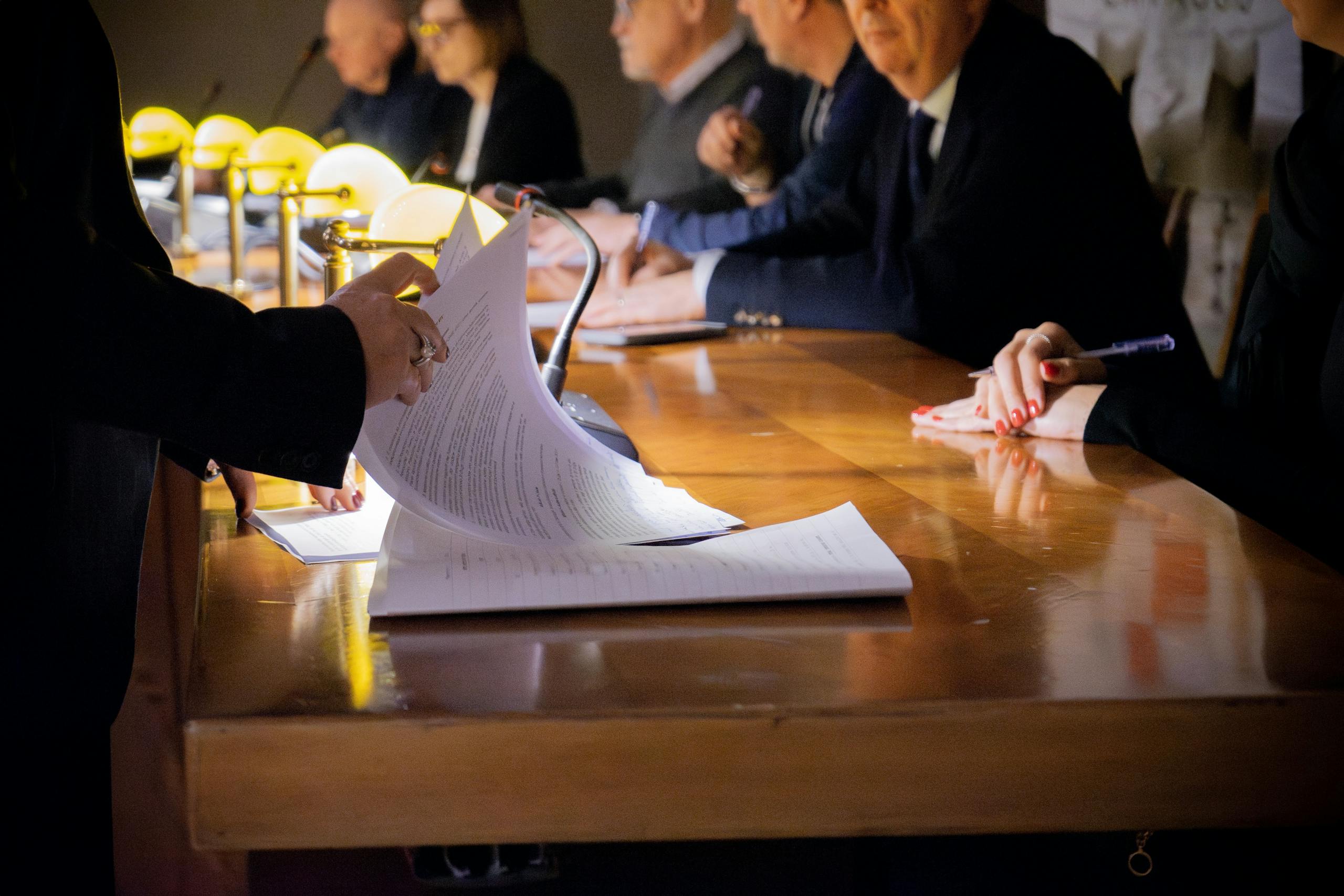 Close-up of a business meeting table with documents being reviewed and signed in Bergamo, Italy.